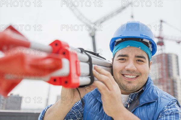 Mixed race worker carrying metal on construction site