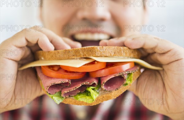 Mixed race man eating sandwich