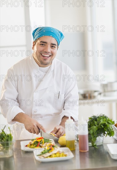 Mixed race chef plating food in restaurant