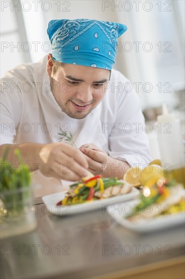 Mixed race chef plating food in restaurant