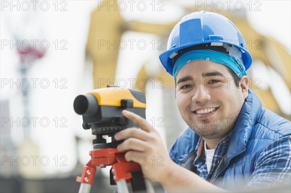 Mixed race engineer using theodolite at construction site