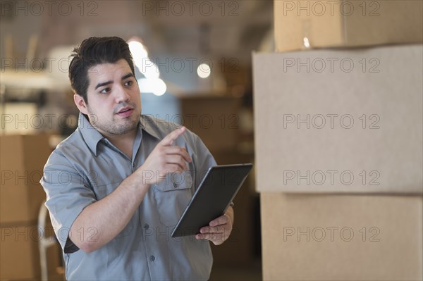 Mixed race worker counting boxes in warehouse