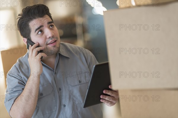 Mixed race worker counting boxes in warehouse