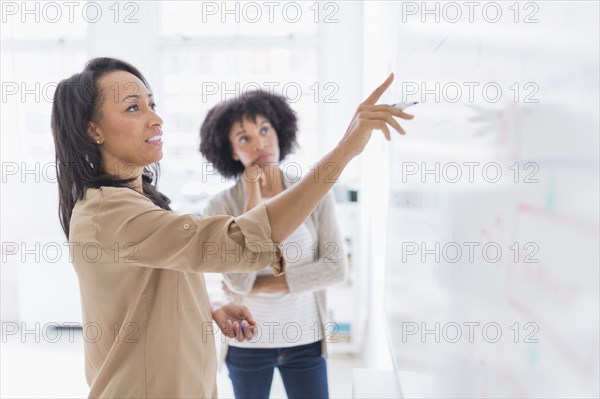 African American businesswomen at whiteboard in office