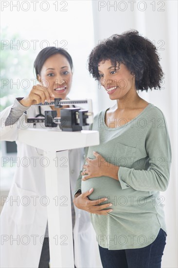 African American doctor weighing pregnant woman