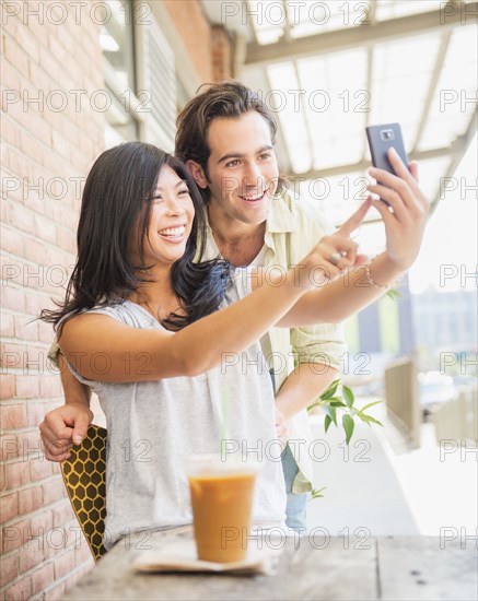 Couple taking self-portrait at sidewalk cafe