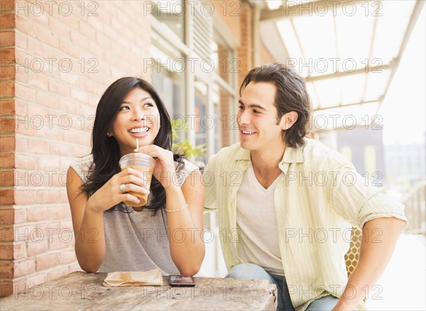 Couple enjoying iced coffee at sidewalk cafe