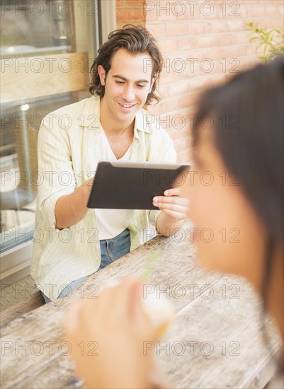 Man using digital tablet at sidewalk cafe