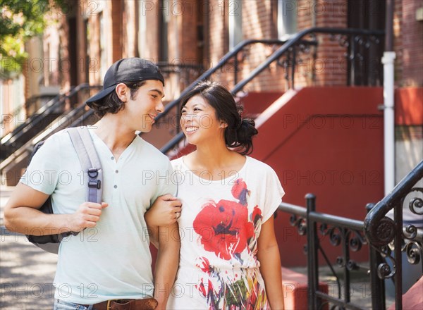 Couple walking on urban sidewalk outside brownstones