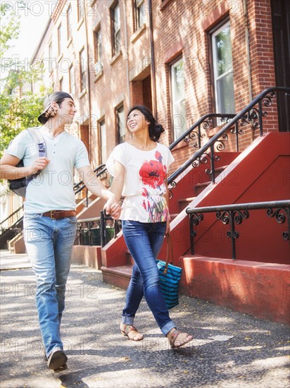 Couple walking on urban sidewalk outside brownstones