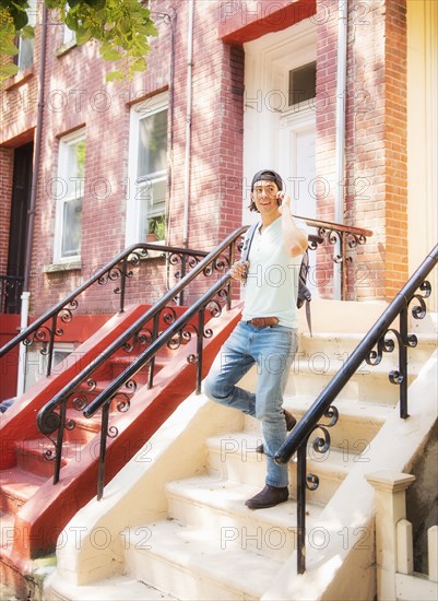 Caucasian man on front stoop of urban brownstone