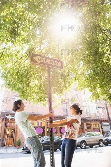 Couple leaning on one way street sign