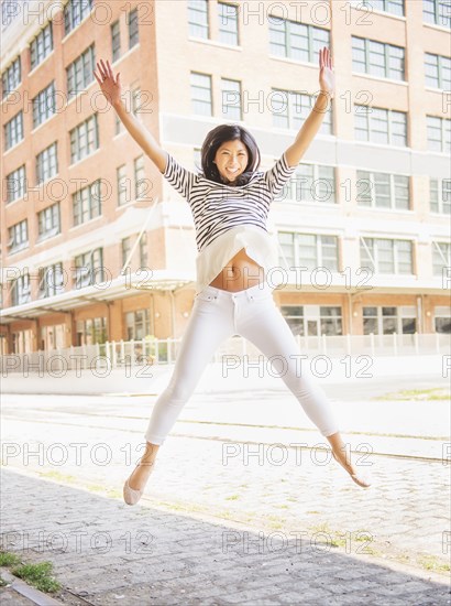 Chinese woman jumping for joy on city street