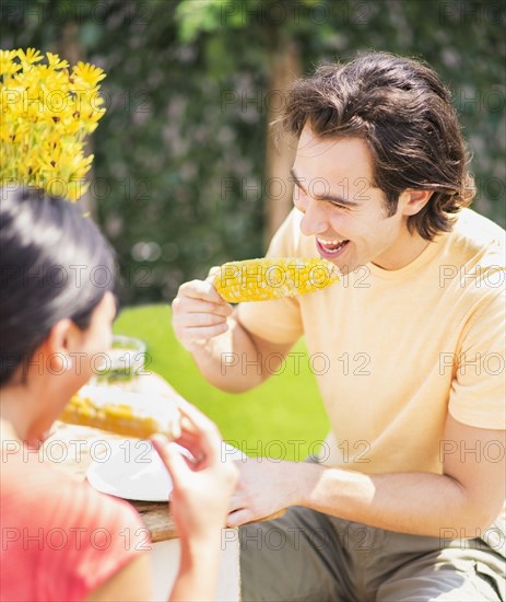 Couple eating corn on the cob outdoors