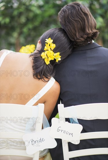 Newlywed couple sitting at wedding reception outdoors