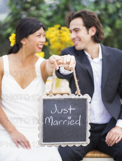 Newlywed couple holding Just Married sign at wedding