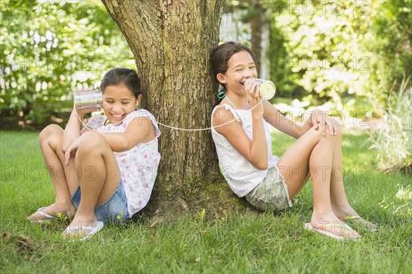 Mixed race girls talking into tin can telephones outdoors