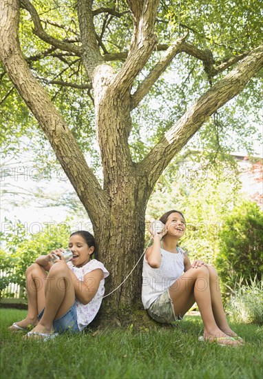 Mixed race girls talking into tin can telephones outdoors