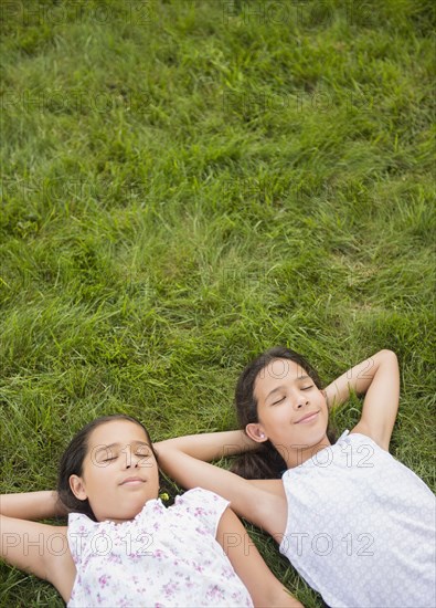 Mixed race girls laying in grass
