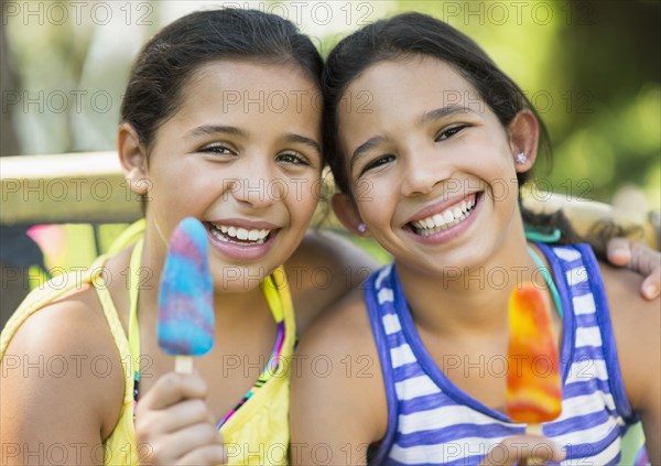 Mixed race girls eating flavored ice outdoors