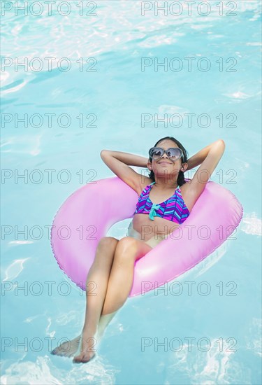 Mixed race girl floating in swimming pool