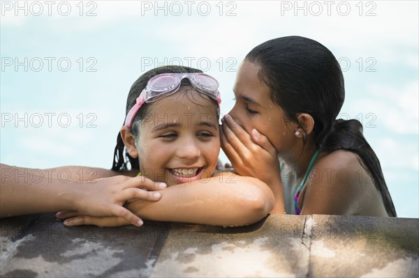 Mixed race girls whispering in swimming pool