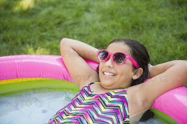 Mixed race girl relaxing in wading pool