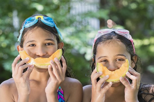 Mixed race girls playing with cantaloupes outdoors
