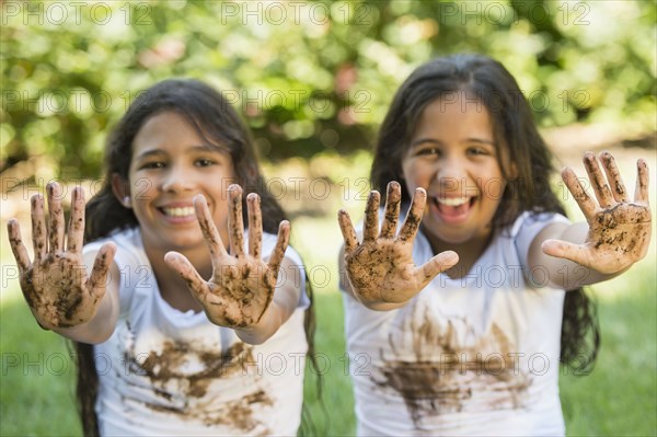 Mixed race girls covered in mud outdoors