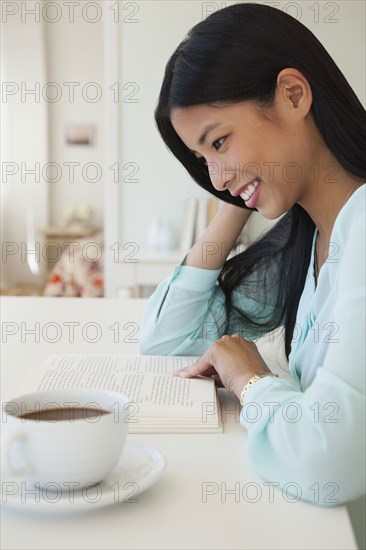 Chinese woman reading with cup of coffee