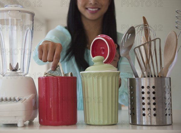 Chinese woman putting money in savings jar