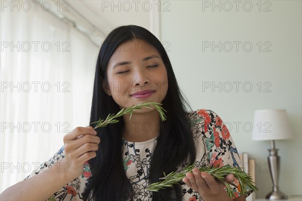 Chinese woman smelling fresh rosemary