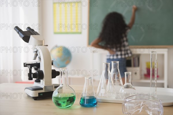 Mixed race student writing on chalkboard in classroom