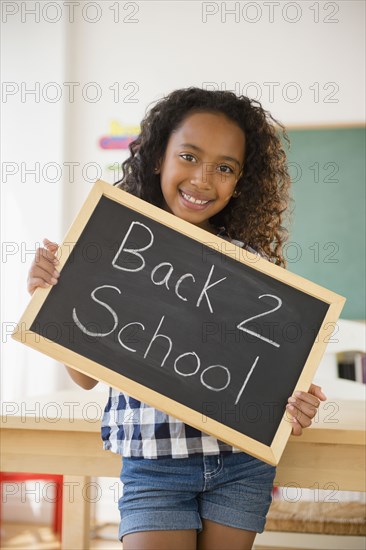 Mixed race student holding blackboard reading back 2 school