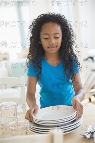 Mixed race girl setting table