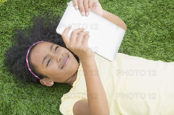 Mixed race girl using digital tablet in grass