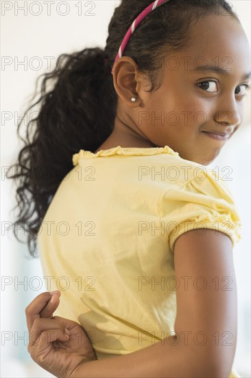 Mixed race girl crossing fingers behind her back