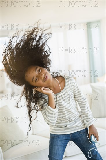 Mixed race girl dancing to headphones in living room