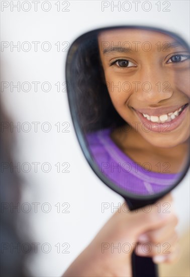 Mixed race girl admiring herself in mirror