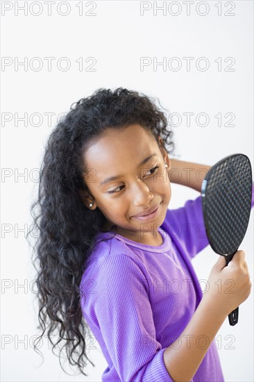 Mixed race girl admiring herself in mirror