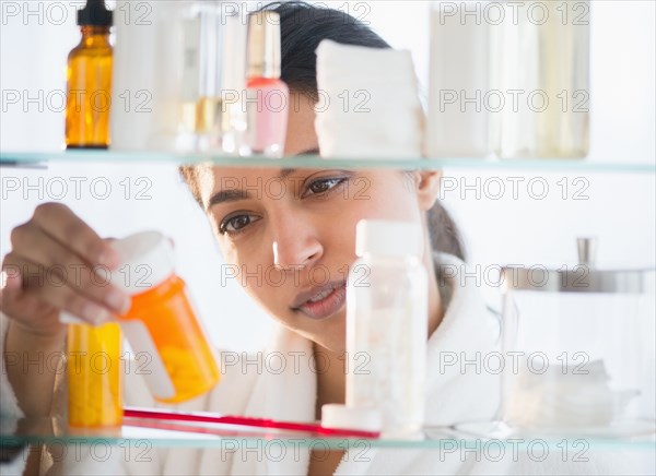 Close up of Asian woman examining label of prescription bottle