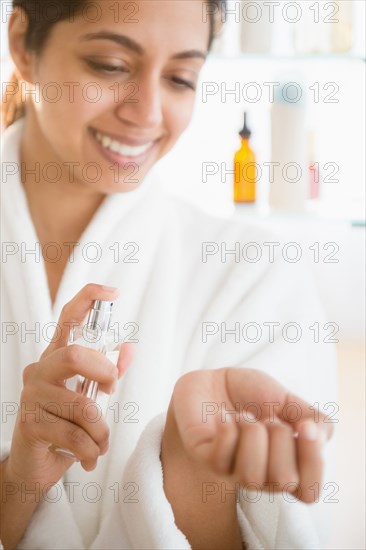 Close up of Asian woman spraying perfume on wrist