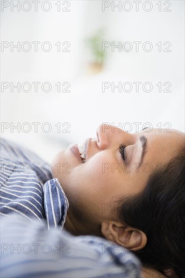 Close up of serene Asian woman laying with hands behind head