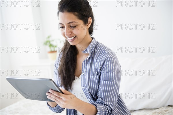 Asian woman using digital tablet in bedroom