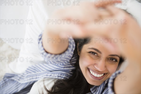 Close up portrait of smiling Asian woman laying in bed