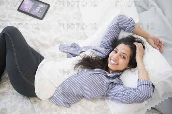 Portrait of smiling Asian woman laying on bed