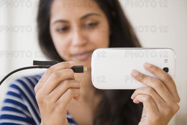 Close up of Asian woman connecting cell phone to battery