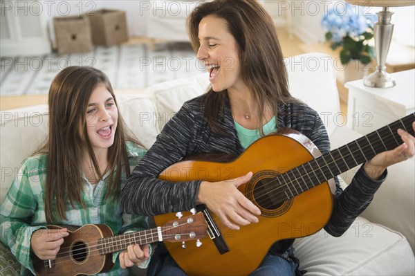 Caucasian mother and daughter singing with guitar and ukulele