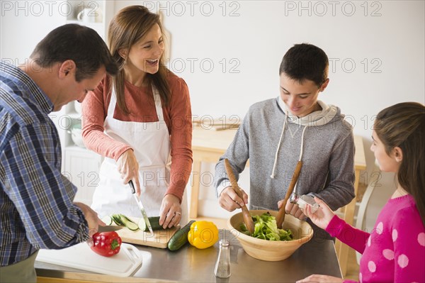 Caucasian family preparing salad in kitchen