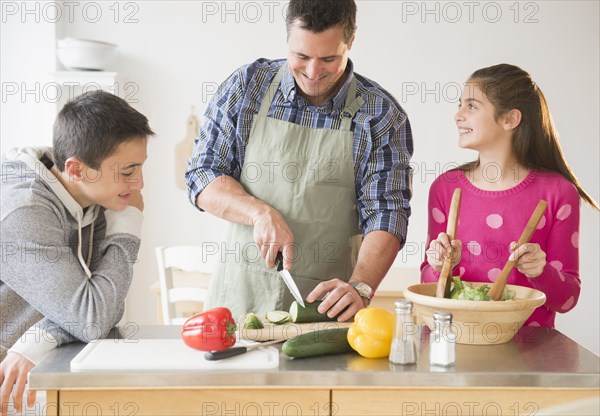 Caucasian father and children preparing salad in kitchen